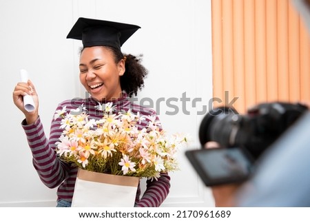 Take a photo of Student in hand raising arms over fist thumb up and holding a bouquet of flowers during commencement success graduate of the university, Concept education congratulation.