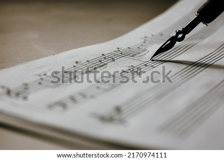 Handwritten music notes macro, music notes with ink pen in the background, selective focus