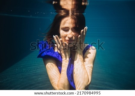 Underwater woman portrait in swimming pool.
