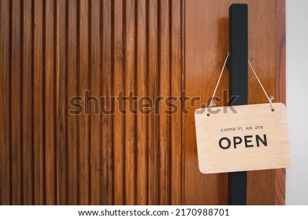 open sign hanging on wood door in front of shop