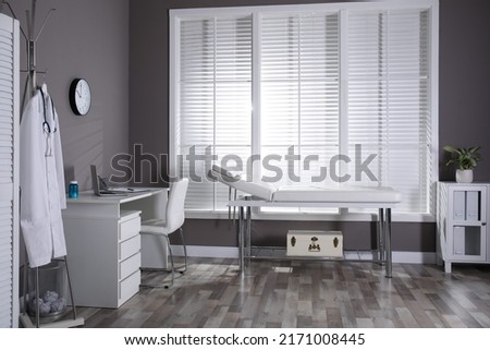 Modern medical office interior with doctor's workplace and examination table Royalty-Free Stock Photo #2171008445