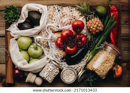 Zero waste food shopping. Fruit and vegetables in cotton bags, pasta, cereals and legumes in glass jars, herbs and spices on wooden background. Healthy food, clean eating, eco friendly, no plastic con Royalty-Free Stock Photo #2171013433