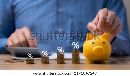 pile of coins and piggy bank, Interest rate and dividend concept Businessman is calculating income and return on investment in percentage. income, return, retirement, compensation fund, investment Royalty-Free Stock Photo #2171047247