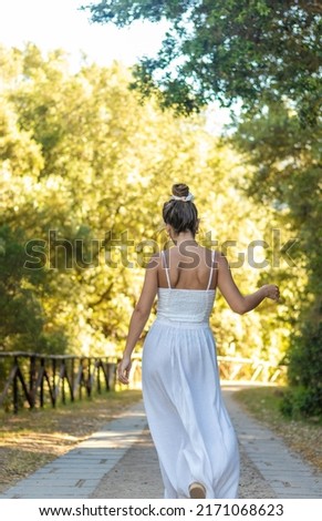 Vertical view of unrecognizable young brunette woman dancing into the nature whearing white dress