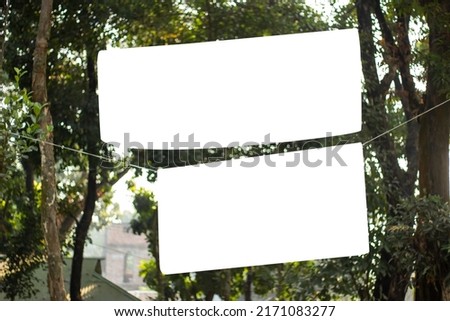 two blank white signboard hanging with a long tree and the background blur.