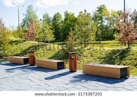Beautiful landscape design of the city park, a pleasant place for walks and recreation of citizens, wooden benches for sitting, a sidewalk in the park. High quality photo