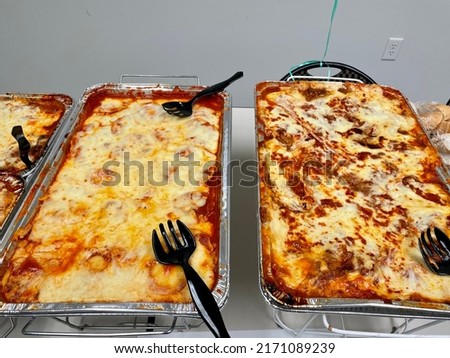 Italian food that has been catered to an office setting. It is set up in aluminum trays on racks with sternos and plastic serving spoons. Royalty-Free Stock Photo #2171089239