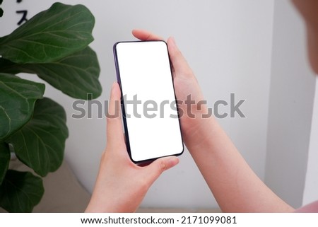 Mockup picture of business woman’s hands holding smart phone with white blank screen in modern place