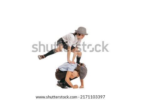 Leapfrog. Happy school age boys, kids wearing retro clothes having fun isolated over white background. Concept of childhood, vintage summer fashion style. Copy space for ad