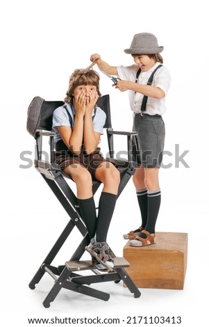 At barber shop. Two school age boys, stylish kids wearing retro clothes, shorts with suspenders isolated over white background. Concept of childhood, vintage summer fashion style. Copy space for ad