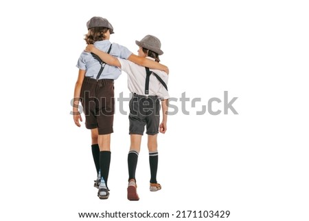 Back view of two school age boys, kids wearing retro clothes isolated over white background. Concept of childhood, vintage summer fashion style. Copy space for ad