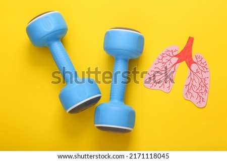 Fitness and lung health concept. Paper cut lungs and dumbbells on yellow background