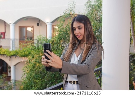 Serious business girl making a video call with her smart phone on a hotel balcony.