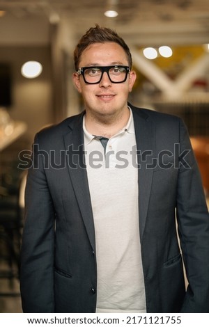 Smiling young businessman in glasses look in camera distance thinking or planning career success. Happy male director or CEO thinking visualizing in office. business vision concept.