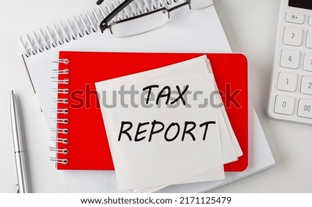 TAX REPORT word on sticker on notepad with pen and calculator