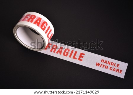 A roll of fragile tape used for securing delicate items for despatch on black background