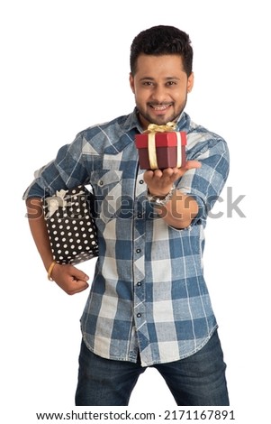 Portrait of young happy smiling handsome man holding gift box and posing on a white background. 