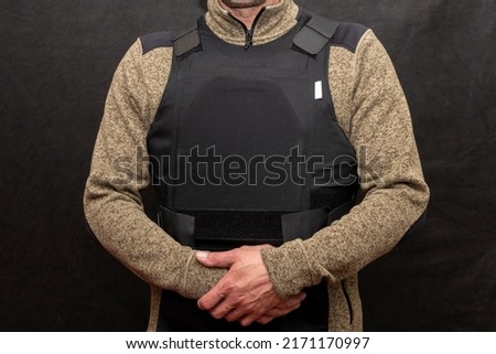 A muscular military man in a bulletproof vest on a black background.