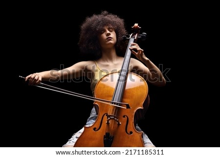 Female artist playing a cello isolated on black background Royalty-Free Stock Photo #2171185311