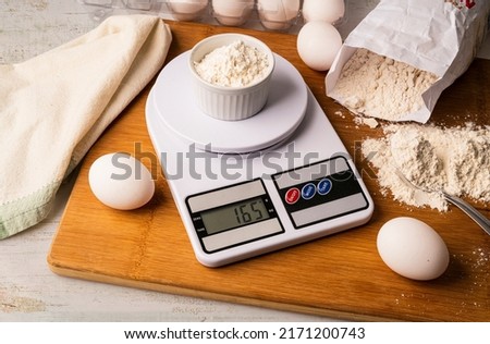 Flour on digital scale with cookie ingredients for baking on wooden table Royalty-Free Stock Photo #2171200743