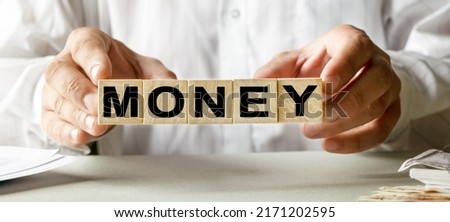 MONEY inscription on the texture of wooden cubes. A business man holds a cube in his hand. An inscription on a financial, business or economic theme.