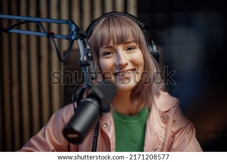 Portrait of female radio host speaking in microphone while moderating a live show Royalty-Free Stock Photo #2171208577