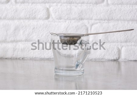 an empty glass ready for brewing herbal tea with metal filter or strainer