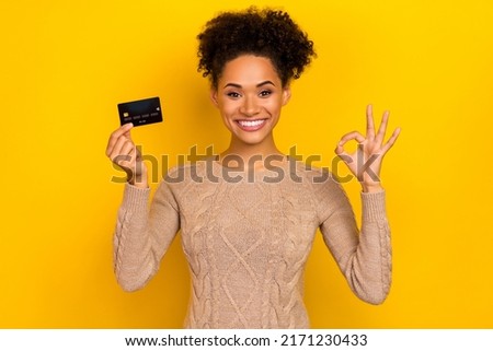Photo of impressed millennial brunette lady hold card show okey wear pullover isolated on yellow color background