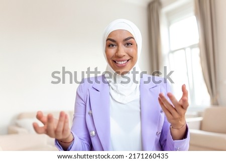Happy pretty Muslim Arabic woman using laptop sitting on cosy sofa. Beautiful young Muslim woman is using a laptop and smiling