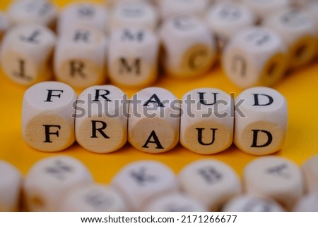 Fraud word concept on wooden cubes blocks. On a yellow background. 