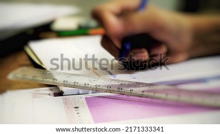 A ruler is placed on a book with a picture of a boy's hands doing homework.