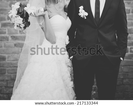 Black and white wedding picture. Newlywed couple together against break wall. 