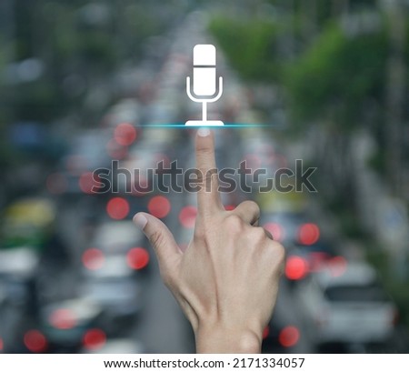 Hand pressing microphone flat icon over blur of rush hour with cars and road in city, Business communication concept