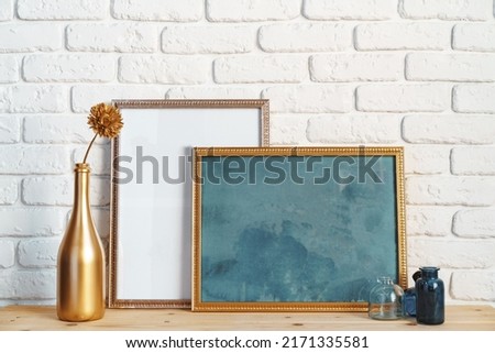 Desk with photo frame and minimal vases against white wall, close up
