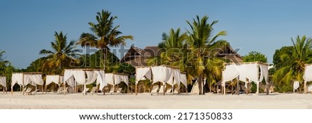 Sun loungers covered with white, airy curtains in a luxurious resort by Kae Beach on Chwaka Bay. Archipelago Zanzibar, Tanzania, Africa
