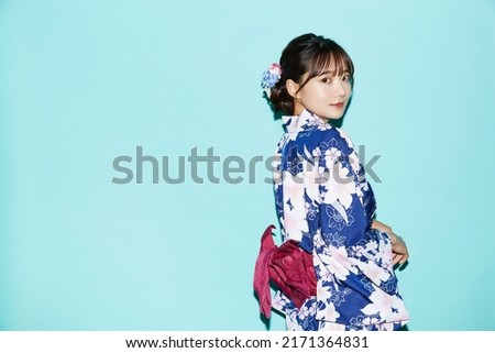 Portrait of young woman in yukata on blue background Royalty-Free Stock Photo #2171364831