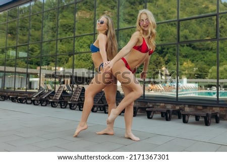 Young female friends in full growth in the pool having fun. Copy space