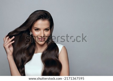 Attractive stylish happy brunette woman with long wavy hair touсhing her hair on white. Hair care and beauty concept.  Royalty-Free Stock Photo #2171367595