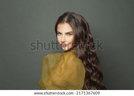 Good looking beautiful brunette woman with long shiny dark wavy hair against black studio wall background Royalty-Free Stock Photo #2171367609