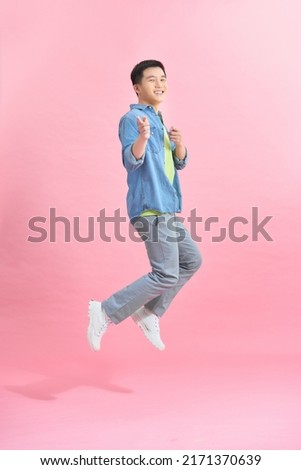Mid-air shot of handsome young man jumping and gesturing against background Royalty-Free Stock Photo #2171370639