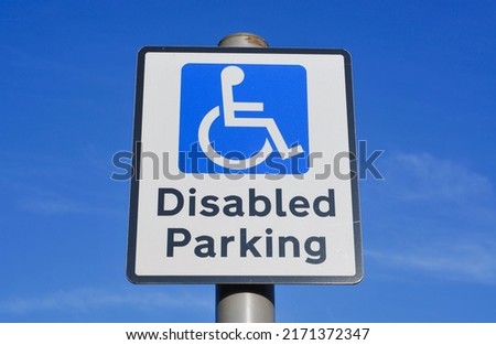 Disabled parking space sign against a clear blue sky.