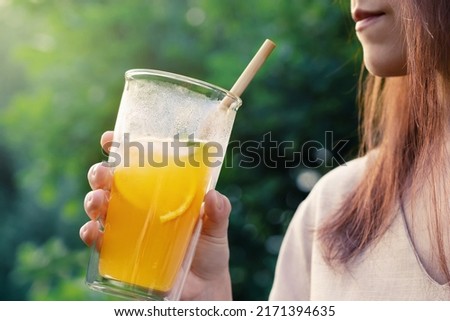Girl holding glass with fresh orange summer cocktail, close-up, selective focus