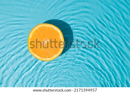 Minimal summer flat lay with half fresh oranges in fresh sunny water. Creative organic fruit background.
