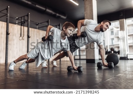 Healthy family concept. Father trainer and teenager son training with dumbbells in gym. Fitness, sports, active lifestyle Royalty-Free Stock Photo #2171398245