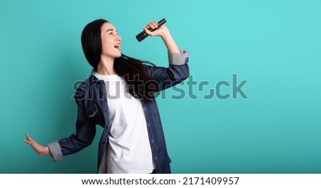Young beautiful asian stylish woman singing karaoke isolated on blue background , Asia woman singing karaoke