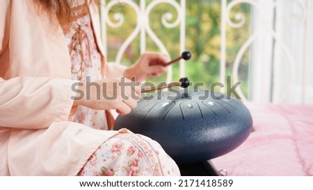 Steel drum playing with stick for hitting as percussion. Steel tongue drum is traditional African instrument as acoustic music for healing and therapy. Royalty-Free Stock Photo #2171418589