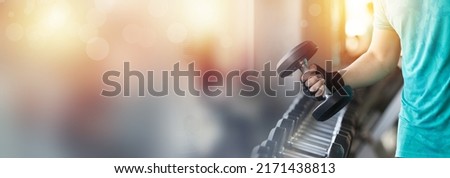 Close up of hand holding metal dumbbell from the rack in the gym. Hand of muscular man picking heavy metal dumbbell in the gym. double exposure with bokeh, banner cover concept. Royalty-Free Stock Photo #2171438813