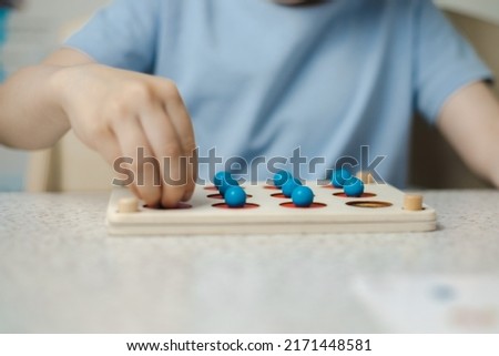 Close-up of the hands of an unrecognizable child playing a game for the development of memory and thinking. Wooden ecological toys. The concept of children's education.
