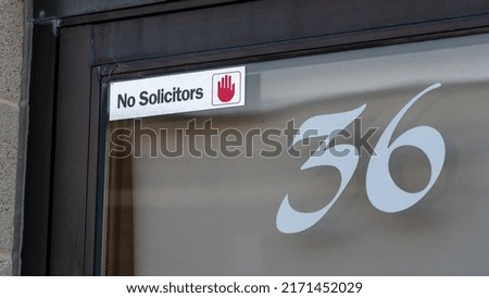 No Solicitors no entry label on a glass door numbered door business door