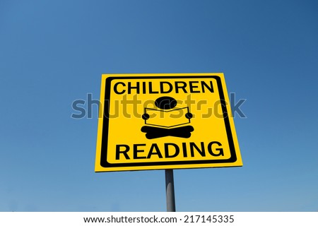 children reading sign with blue sky                              
